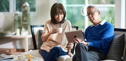 Man and woman on the couch, looking at iPad.