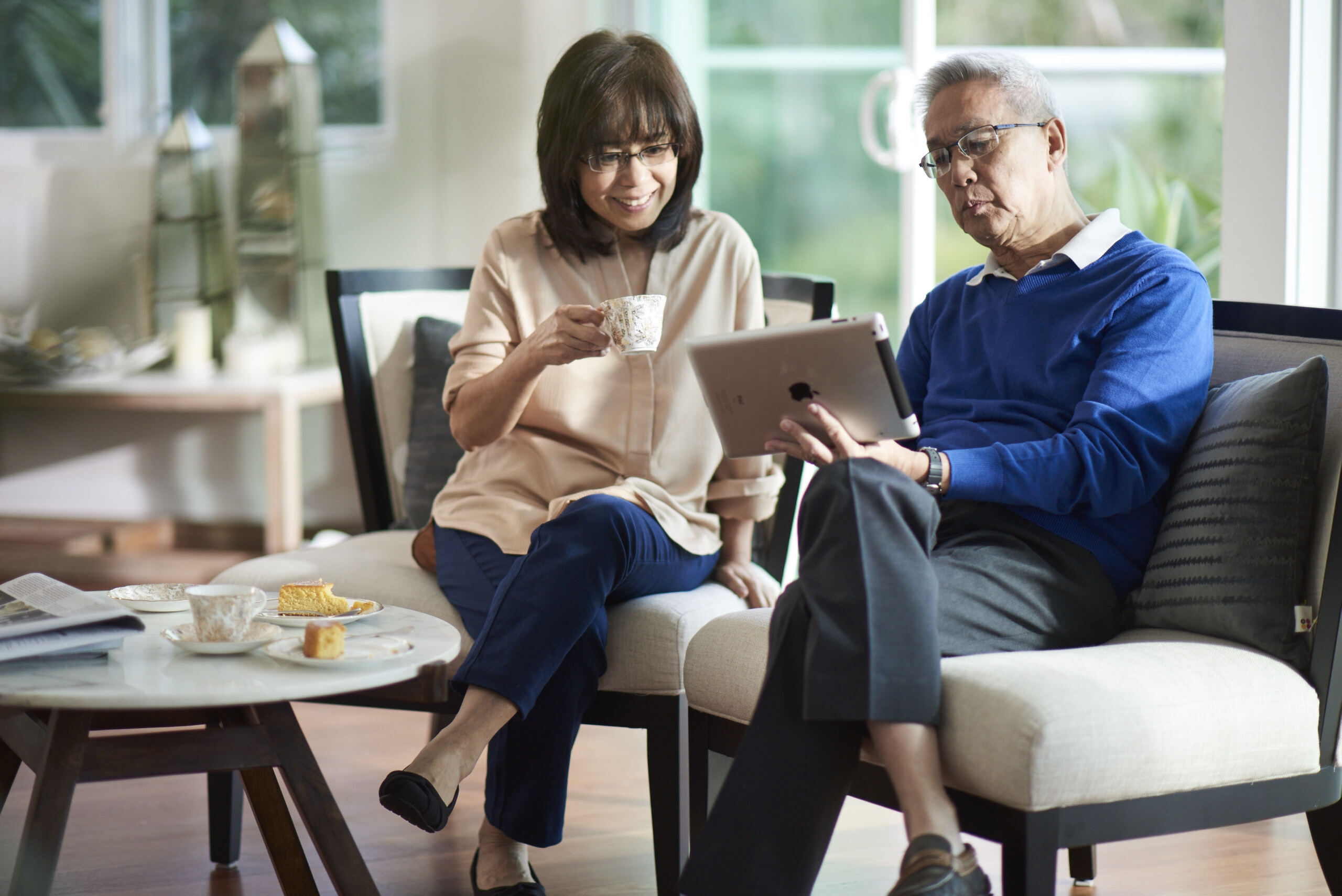 Man and woman on the couch, looking at iPad.